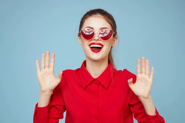 Mooie vrouw in donker bril rood shirt helder make-up emoties aantrekkelijk kijken blauw achtergrond — Stockfoto