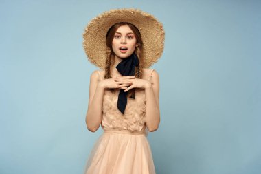 Mavi arka planda pembe elbiseli bir kız elleriyle romantik modeller yapıyor.