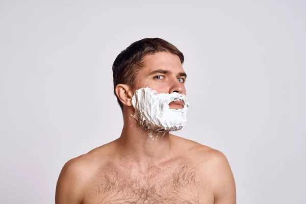 Knappe man met wit scheerschuim op zijn gezicht en schone huid met scheermesjes die kale schouders verzorgen — Stockfoto