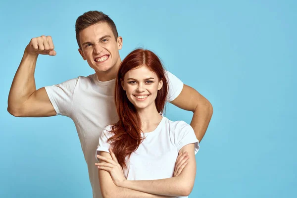 파란색 배경에 팔 근육을 보이는 건장 한 남자와 젊은 여자가 절뚝거리는 모습 — 스톡 사진