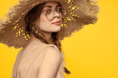 Saçları örgülü ve sarı arka planda şapkası olan güzel bir kadının portresi.