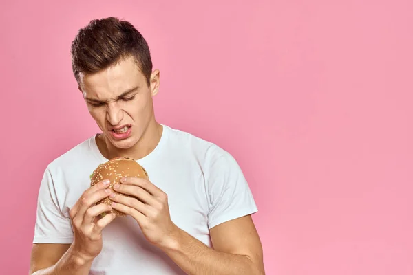 Hombre con hamburguesa grande sobre el fondo rosa calorías comida rápida vista recortada Copia Espacio de cerca — Foto de Stock