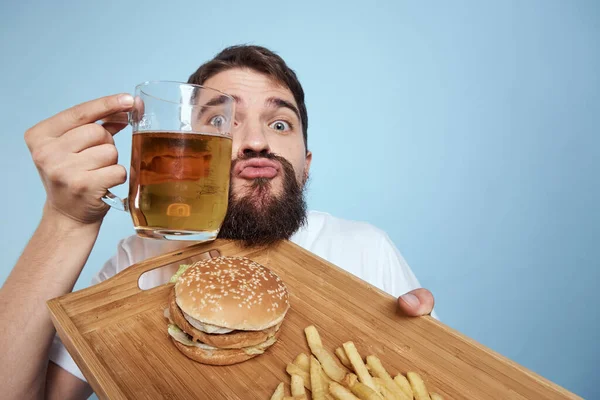 Vrolijke man bier mok hamburger frites fast food dieet blauw achtergrond close-up — Stockfoto
