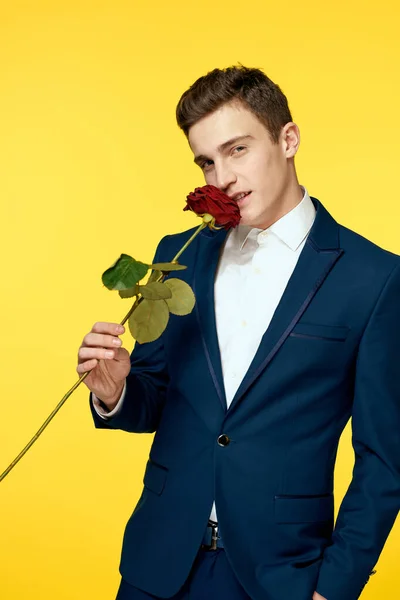 Herren im klassischen Anzug auf gelbem Hintergrund und roter Rose Romantik ausgeschnitten Ansicht Modell Porträt. — Stockfoto