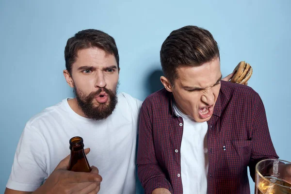 Deux amis ivres joyeux buvant de la bière mode de vie émotions sur un fond bleu — Photo