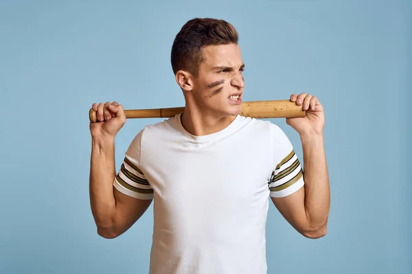 Ragazzo del baseball con un pipistrello in mano su uno sfondo blu e un colore di combattimento sulla sua t-shirt modello trucco viso — Foto Stock