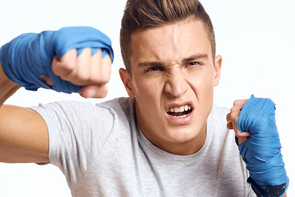 Boxeador masculino deportivo con guantes azules practicando golpes sobre un fondo claro recortado vista — Foto de Stock