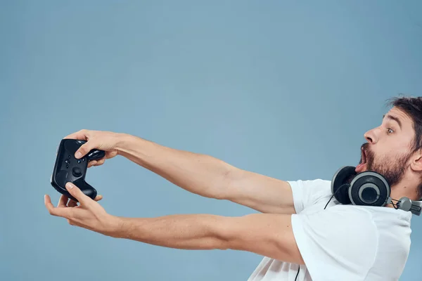 Un hombre con un controlador en sus manos auriculares juegos hobby ocio tecnología estilo de vida fondo azul —  Fotos de Stock