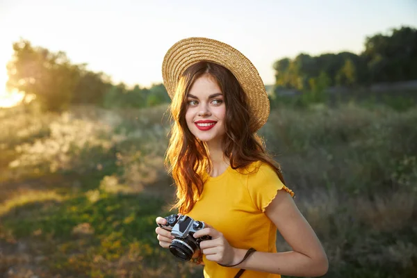 Mulher bonita com câmera na natureza chapéu de ar fresco lábios vermelhos passatempo — Fotografia de Stock