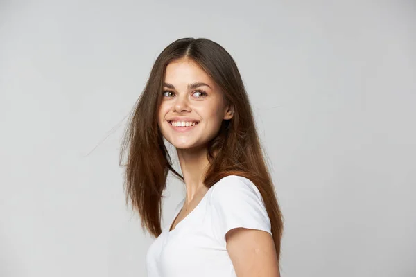 Mulher feliz sorrindo e olhando para o lado em um fundo leve vista cortada — Fotografia de Stock