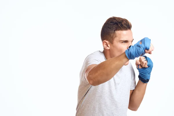 Boxeador masculino deportivo con guantes azules practicando golpes sobre un fondo claro recortado vista — Foto de Stock