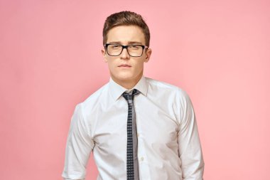 Beyaz gömlekli, kravatlı, gözlüklü, kendine güvenen, resmi pembe arka planlı bir iş adamı.