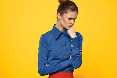 Mavi gömlekli, parlak makyajlı, kırmızı dudaklı, sarı arkaplan manzaralı bir kadın portresi