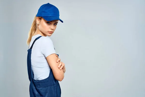 Kvinna i arbete uniform blå mössa tjänst leverans service ljus bakgrund — Stockfoto