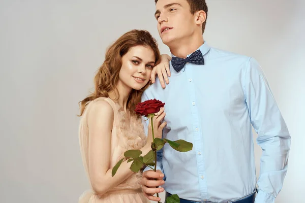 Sevgi dolu genç bir çift ellerinde kırmızı bir gül ve açık bir arka plan romantizmi — Stok fotoğraf