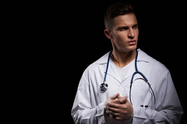 Medico professionista in un abito medico con uno stetoscopio intorno al collo contro uno sfondo scuro vista ritagliata — Foto Stock