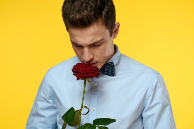 Sarı arka planda kırmızı gül ve açık gömlek papyonlu bir beyefendinin portresi.