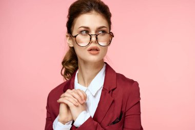 Kırmızı ceketli zarif bir kadın. Gözlüklü. Ofis müdürü, pembe arka plan.