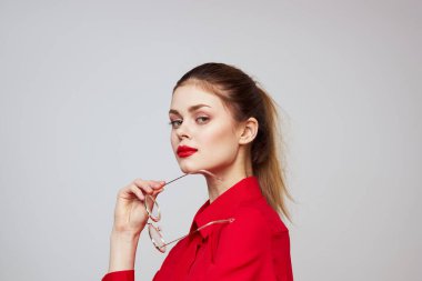 Kırmızı gömlekli şık bir kadın açık arkaplanda eğlenceli duygular parlak makyaj gözlükleri çekici bir görünüş. 