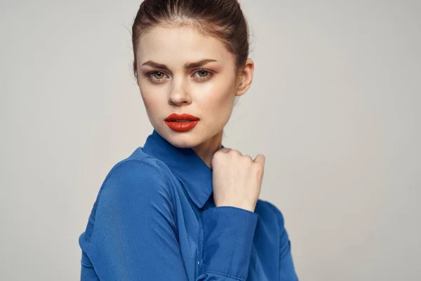 Portret van een mooie vrouw met rode lippen op een lichte achtergrond en een blauw shirt bijgesneden uitzicht — Stockfoto