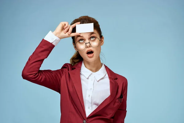 Zakelijke vrouw rood jasje visitekaartje bril uitvoerende blauw achtergrond — Stockfoto