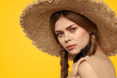 Sarı arka planda saman şapkalı portre kadın. Yazlık elbise mankeni romantizmi.