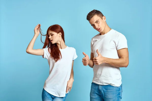 Porträtt av en tjej och en kille med blå bakgrund i vita t-shirts och jeans beskuren vy över vänner — Stockfoto