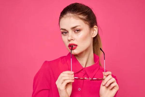 Mulher de moda em camisa rosa com óculos nas mãos sobre fundo isolado vista cortada — Fotografia de Stock