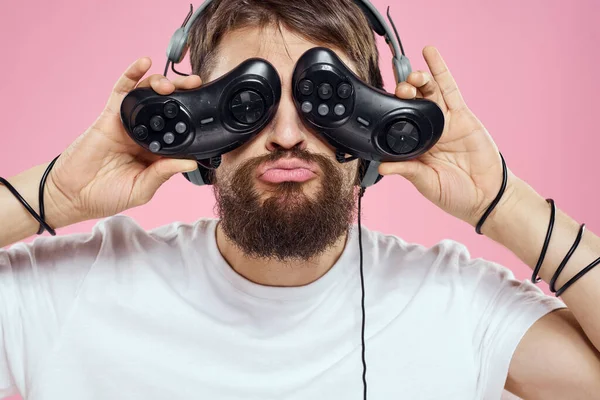 Man in hoofdtelefoon met joysticks in handen spelen spelletjes lifestyle plezier entertainment roze achtergrond — Stockfoto