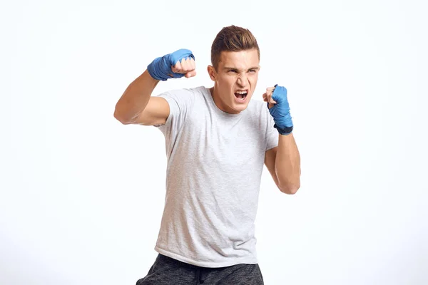 파란 장갑을 끼고 가벼운 배경 화면에 펀치를 불고 연습하고 있는 산적 한 남성 권투 선수 — 스톡 사진