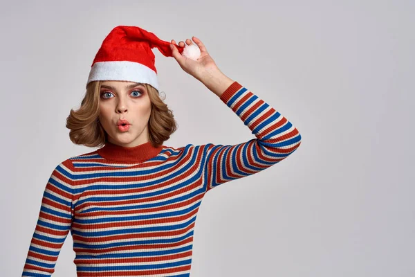 Glückliche Frau mit Weihnachtsmütze und gestreiftem Pullover gestikuliert mit den Händen zum Jahreswechsel — Stockfoto