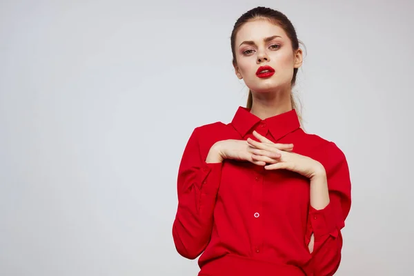 Una hermosa chica con labios rojos y una camisa sobre un fondo claro gestos con sus manos — Foto de Stock