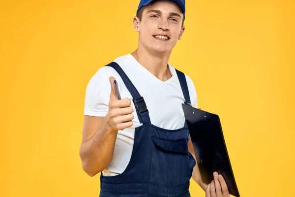 Man in het werken uniforme documenten weergave van diensten bezorgdienst gele achtergrond — Stockfoto