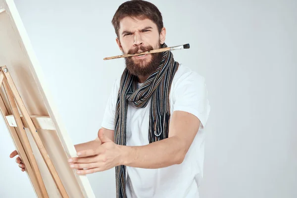 Un artista hombre se basa en un caballete una bufanda blanca camiseta arte afición creatividad — Foto de Stock