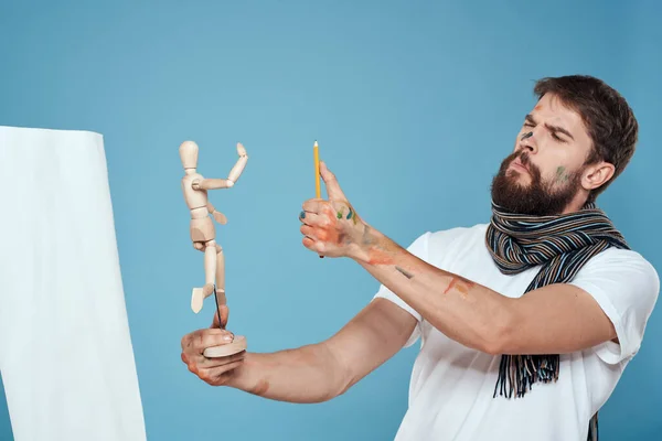 Artista masculino con un maniquí de madera en las manos dibujo Pasatiempo creativo fondo azul — Foto de Stock