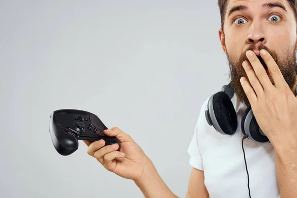 Mann mit Gamepad-Kopfhörer spielt Freizeittechnik weißes T-Shirt heller Hintergrund — Stockfoto