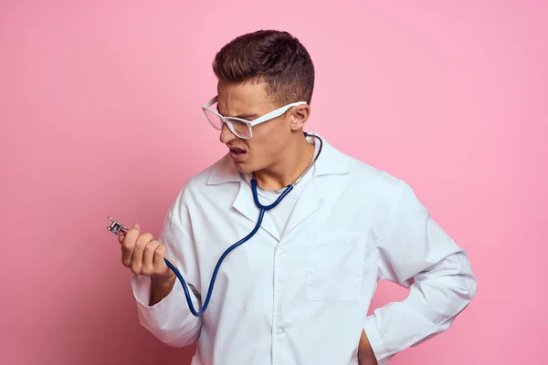 Jeune médecin avec un stéthoscope et des lunettes sur fond rose infirmière stagiaire modèle — Photo