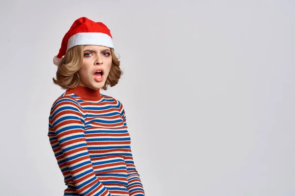 Happy woman in a Christmas cap and a striped sweater gestures with her hands for the New Year holidays — Stock fotografie