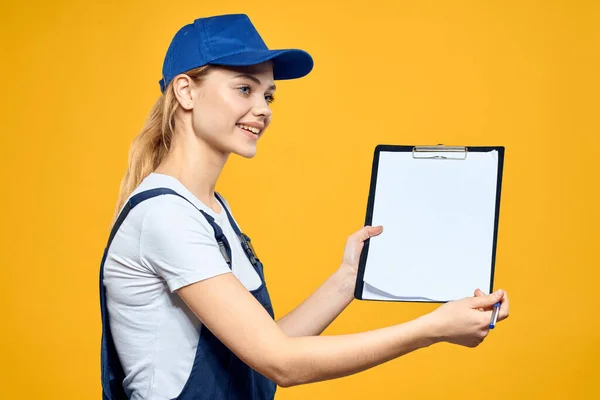 Woman in work uniform documents courier service yellow background — Stock Photo, Image