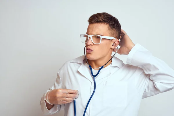 Médecin dans une robe médicale avec un stéthoscope et des lunettes sur un fond clair portrait de vue recadrée — Photo