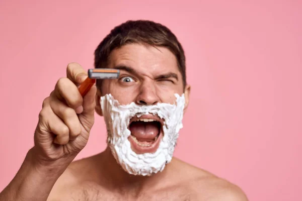 Man med rakhyvel och vitt skum på ansiktet rosa bakgrund naken bål bad behandlingar — Stockfoto
