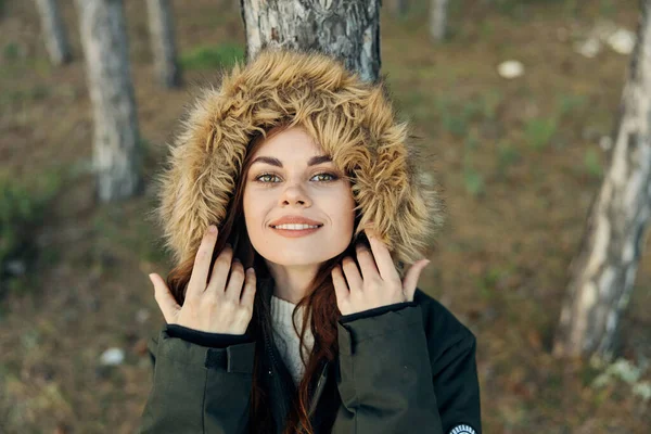 A woman with a hood on her head in nature is leaning against a tree in the forest — Stock Photo, Image