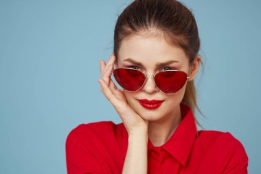 Gözlüklü ve kırmızı dudaklı bir kadının portresi. Mavi arka plan modeli.