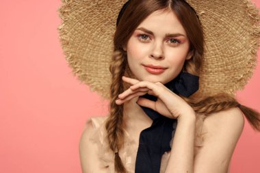 Hasır şapkalı bir kızın portresi pembe arka plan duyguları yakın plan güzel yüz modeli örgüler.