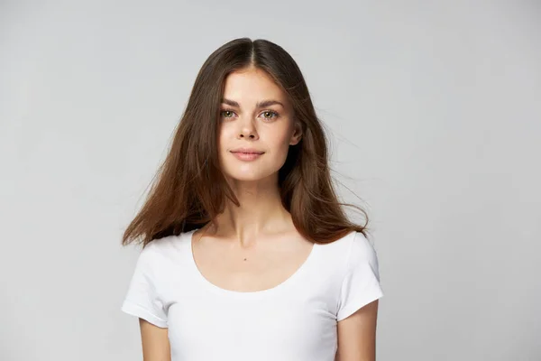 Una bella ragazza bruna con i capelli lunghi in una t-shirt bianca guarda avanti — Foto Stock