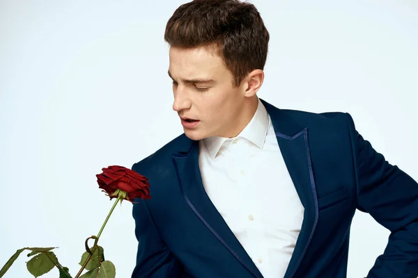 Ein Mann im Anzug mit einer Rose in der Hand ein Geschenk Datum Licht Hintergrund — Stockfoto