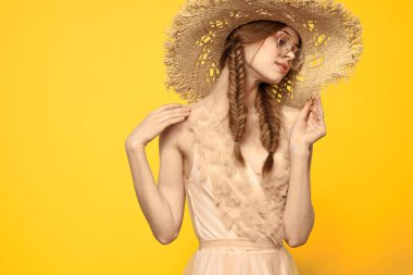 Sarı arka planda saman şapkalı portre kadın. Yazlık elbise mankeni romantizmi.