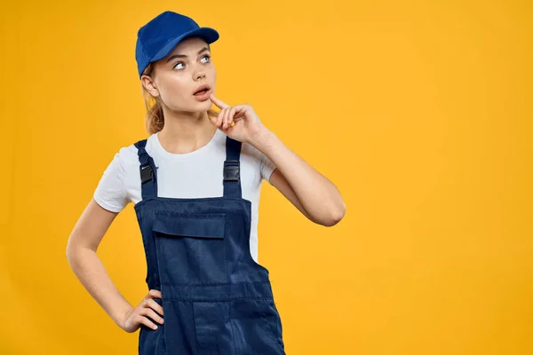 Женщина в рабочей форме голубая кепка доставки курьерской службы желтый фон — стоковое фото