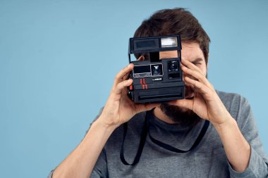 Profesyonel bir kamerayla elinde profesyonel bir fotoğrafçı hobi olarak yaratıcılığın mavi arka planına yaklaşıyor.