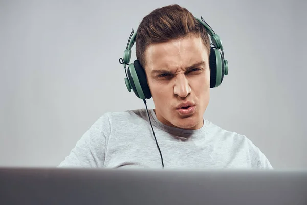 Een man op de bank voor een laptop met een joystick in een videogame technologie hoofdtelefoon — Stockfoto